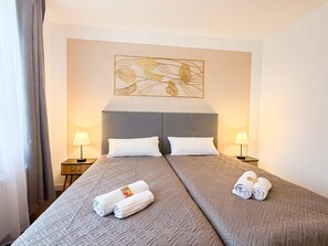 A hotel room with two beds, a large artwork above the headboard, and two bedside lamps.