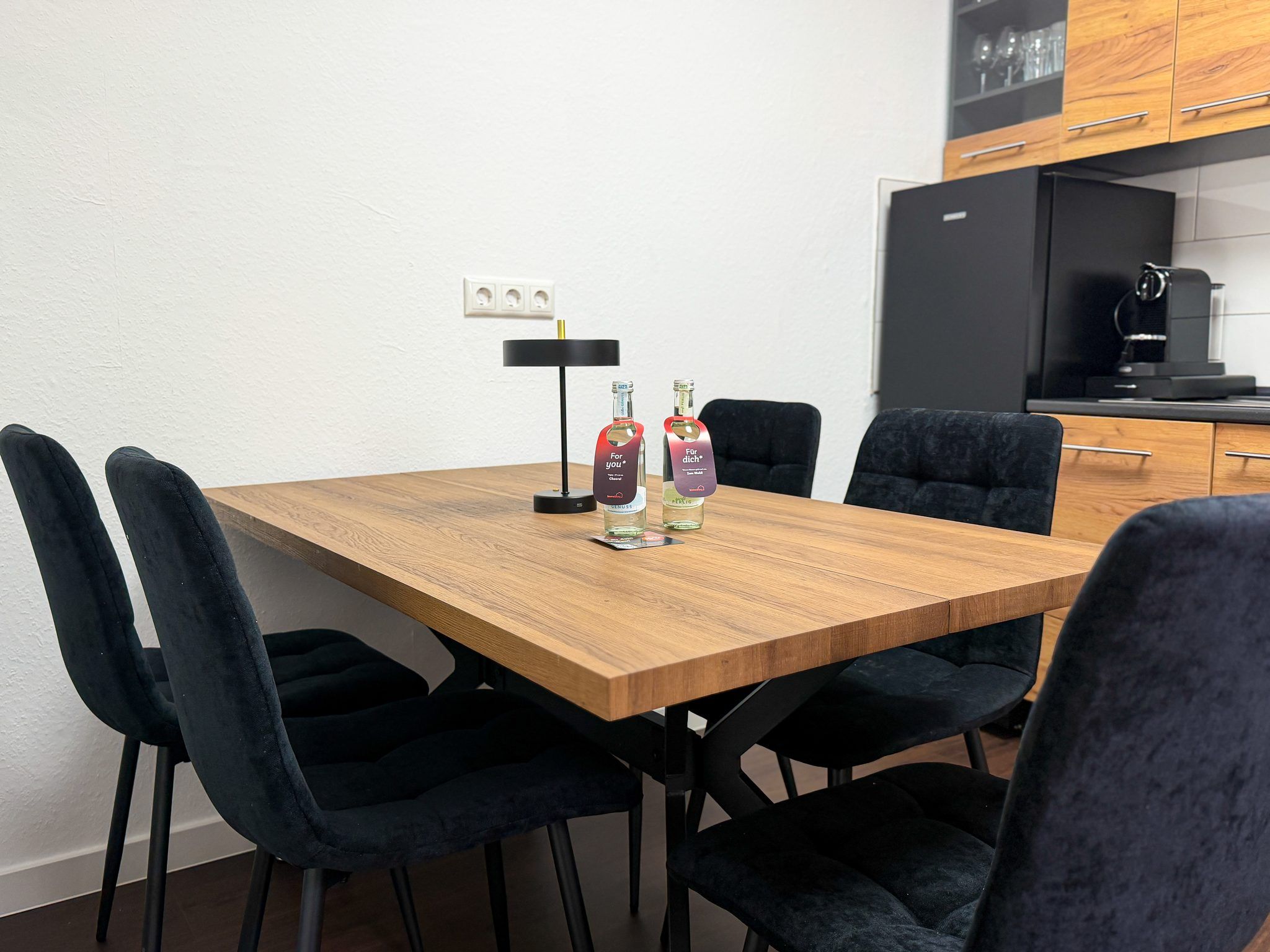 A dining table with chairs, a lamp, and two bottles of liquor.