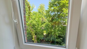 Una finestra amb vista a un jardí i arbres.