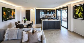 Una cocina moderna con armarios oscuros, una isla central y un comedor con una mesa redonda y sillas.
