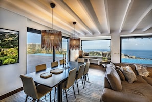 Un interior moderno con comedor, asientos y vistas al mar.