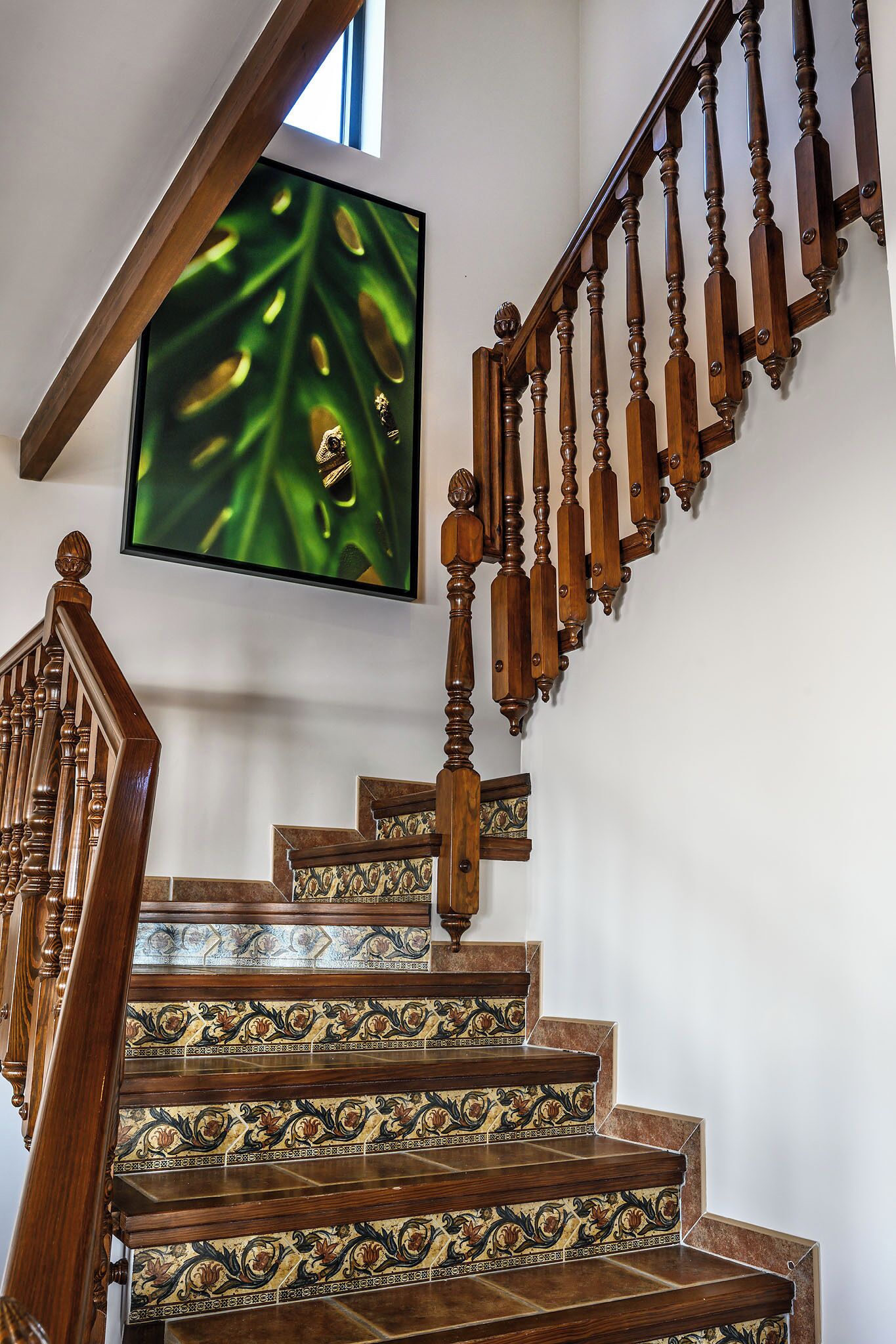 Una escalera de madera con barandillas ornamentales y un diseño de azulejos decorativos en los peldaños.