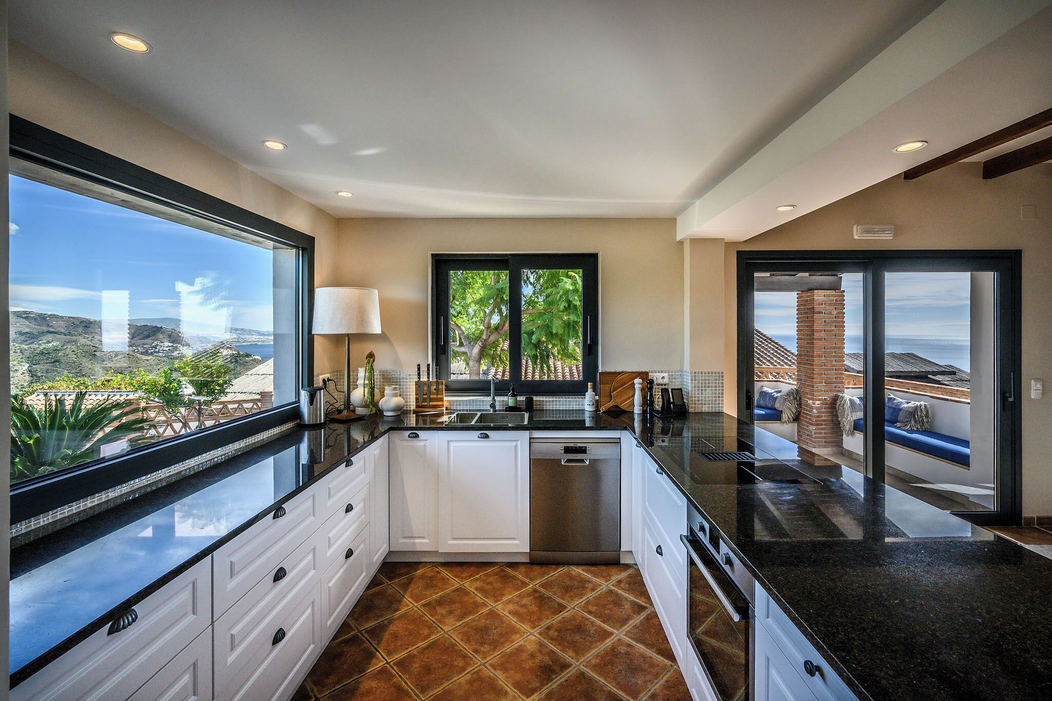 Cocina moderna con vistas al paisaje, lavavajillas y un amplio ventanal.