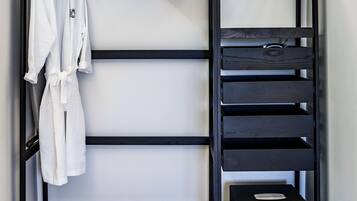 Un armario metálico negro con varios estantes y una barra para colgar, que contiene una bata blanca y un pequeño dispositivo electrónico.
