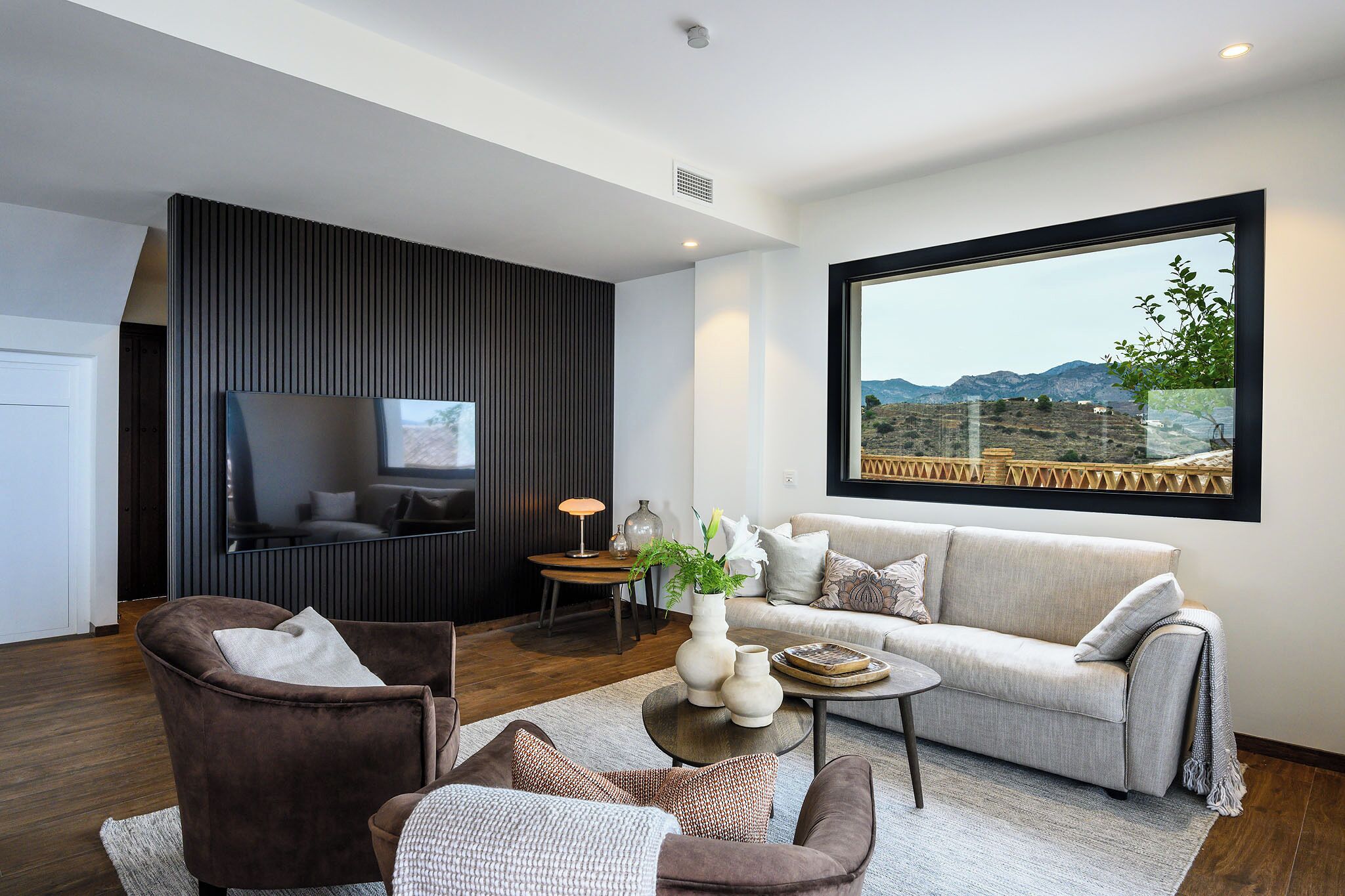 Un salón moderno con sofá, sillones, una mesa de centro y televisor.