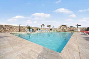 Ein Swimmingpool mit Liegestühlen und einer Steinmauer.