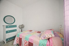 A bedroom with a bed, a dresser, a fan, and a mirror. - Holiday Home 'La Chumbera' with Shared Pool and Private Terrace (Vejer de la Frontera)