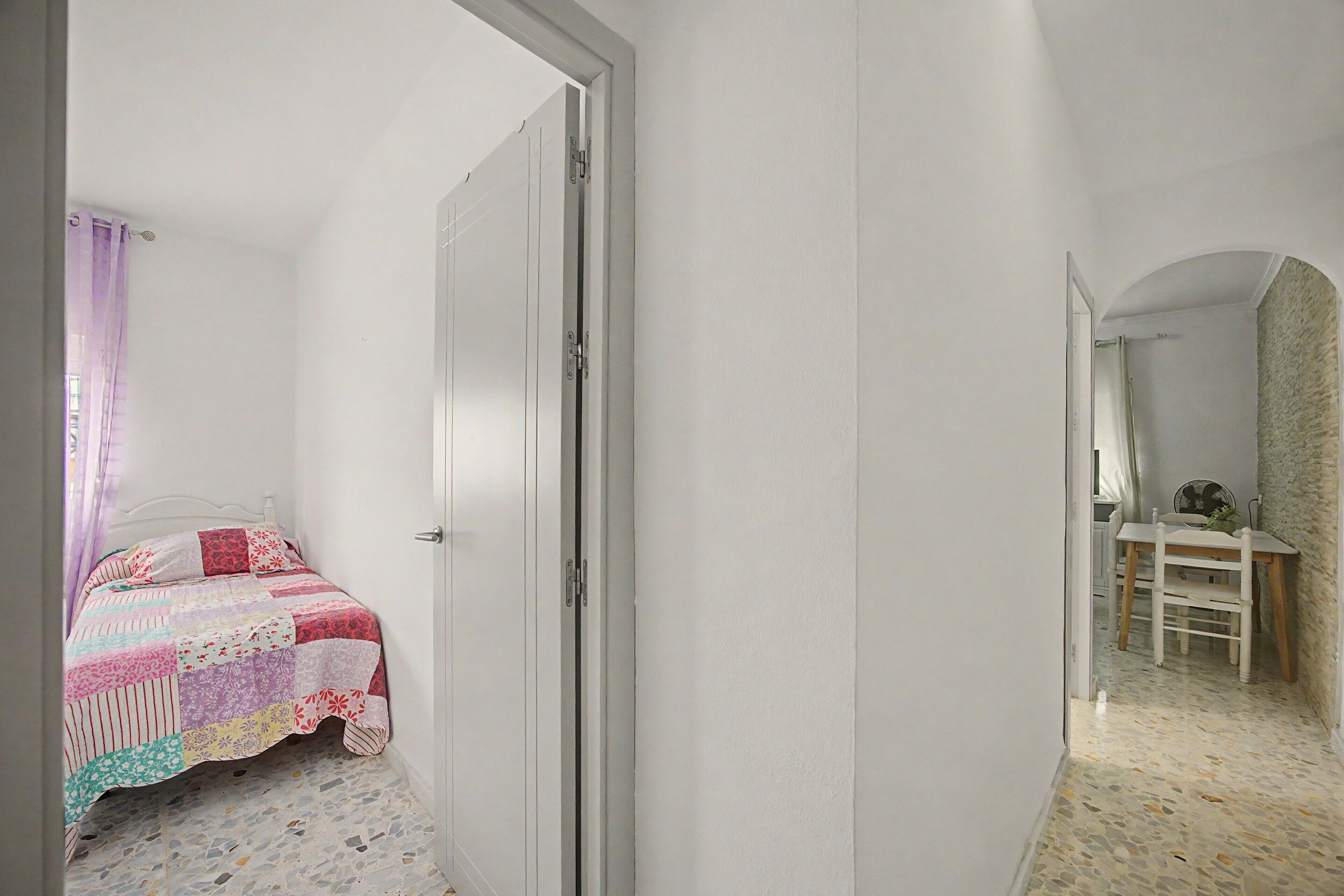 Una camera da letto con un letto, una porta e un tavolino con una sedia.