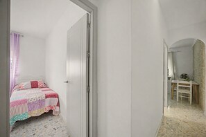 Un dormitorio con cama, una puerta y una pequeña mesa con silla.