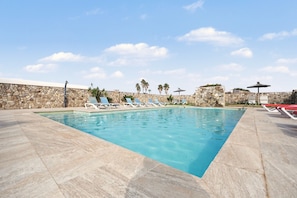 A swimming pool with lounge chairs and a stone wall. - Holiday Home 'La Chumbera' with Shared Pool and Private Terrace (Vejer de la Frontera)