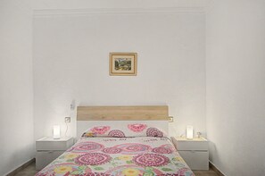 Een slaapkamer met een bed, twee nachtkastjes, een wanddecoratie en een bedlamp.