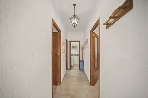 Een hal met houten deuren, een betegelde vloer en een hanglamp.