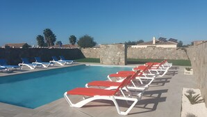 A swimming pool with sun loungers, a stone wall, and a clear sky. - Holiday Home 'Casa El Arriate' with Shared Pool and Private Terrace (Vejer de la Frontera)