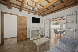 A living room with a wooden ceiling, a television, a glass coffee table, and a sofa. - Holiday Home 'Casa El Arriate' with Shared Pool and Private Terrace (Vejer de la Frontera)