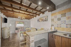 A kitchen with a stone island, wooden beams, and a tiled backsplash. - Holiday Home 'Casa El Arriate' with Shared Pool and Private Terrace (Vejer de la Frontera)