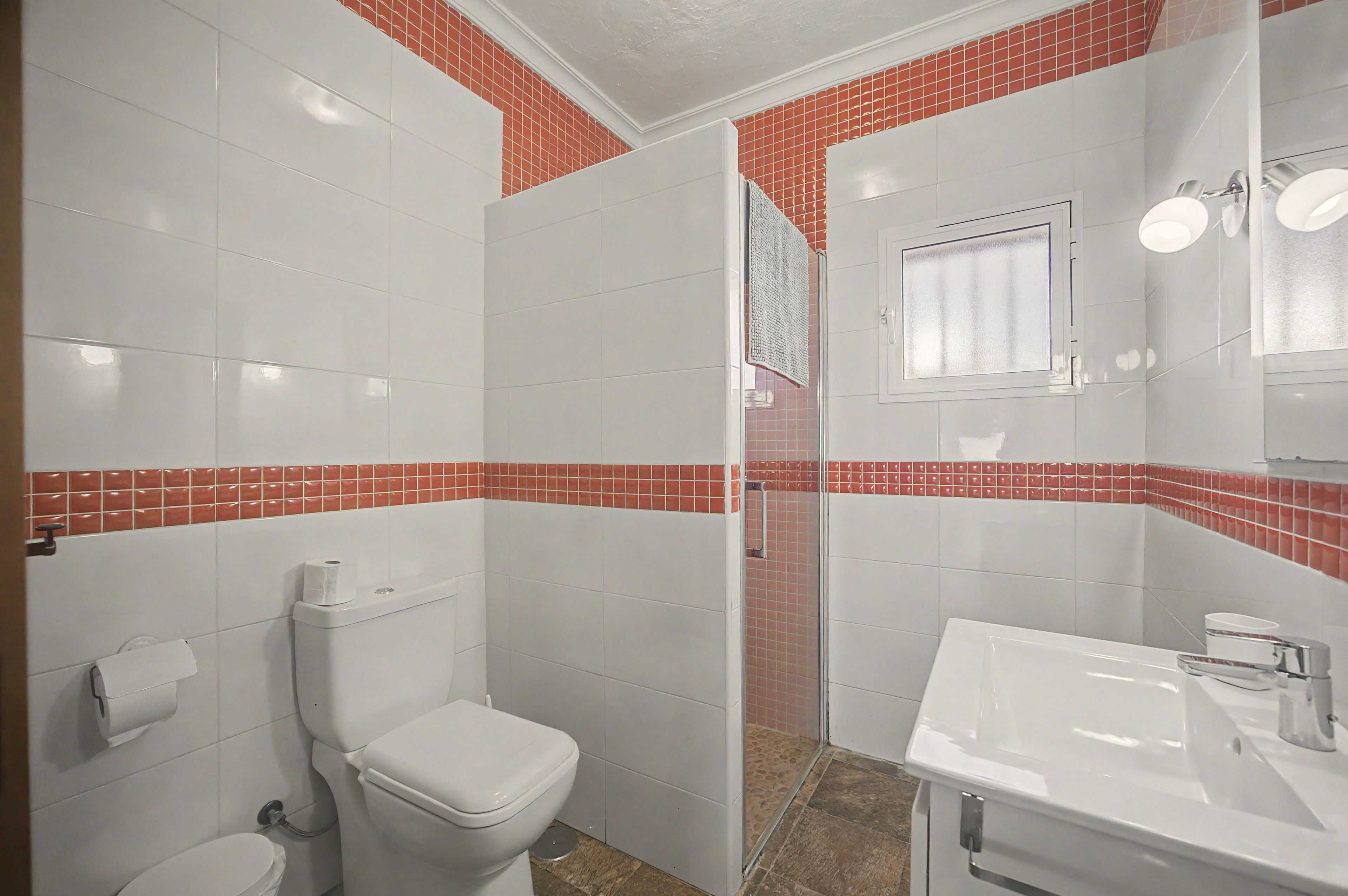 Un baño con inodoro, lavamanos y zona de ducha.