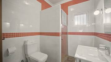 Un baño con inodoro, lavamanos y zona de ducha.
