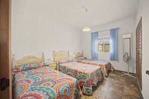 Een kamer met twee houten bedden, een plafondventilator en een raam met gordijnen.