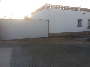 Un edificio con una reja blanca cerrada, base de piedra y un área pavimentada con un diseño circular.
