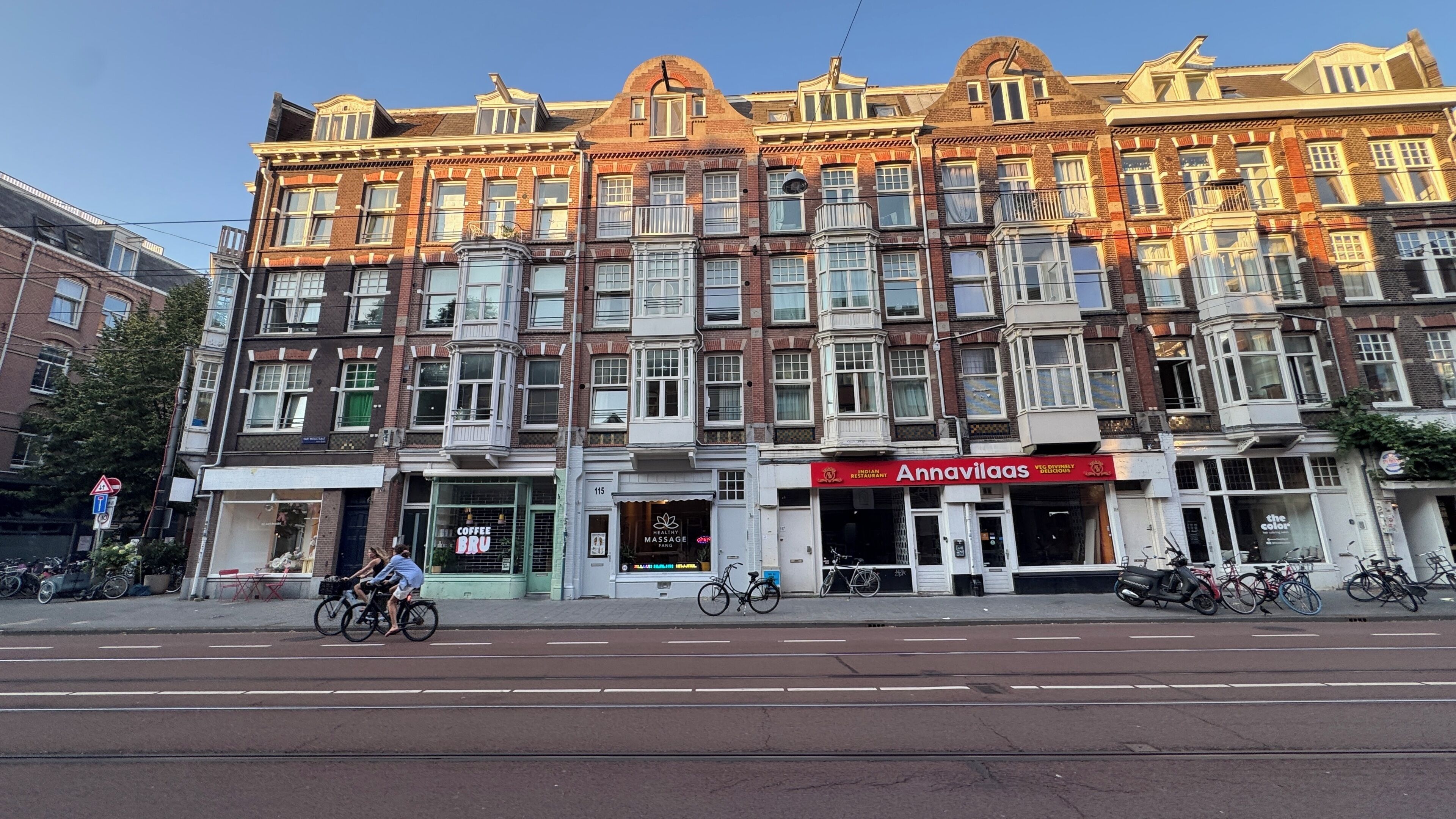 A row of traditional brick buildings with ground-floor shops, including a coffee shop and a massage parlor.