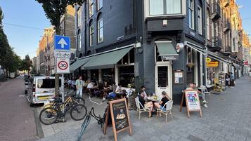 A street with outdoor seating at a restaurant, bicycles parked, and a clear sky.