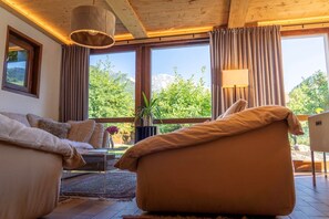 A cozy living room with a sofa, a chair, a table, and a potted plant. - Charming chalet (Saint-Gervais-les-Bains)