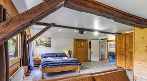 A cozy bedroom with a wooden bed, a small bedside table, a nightstand, and a window with curtains. - Charming chalet (Saint-Gervais-les-Bains)