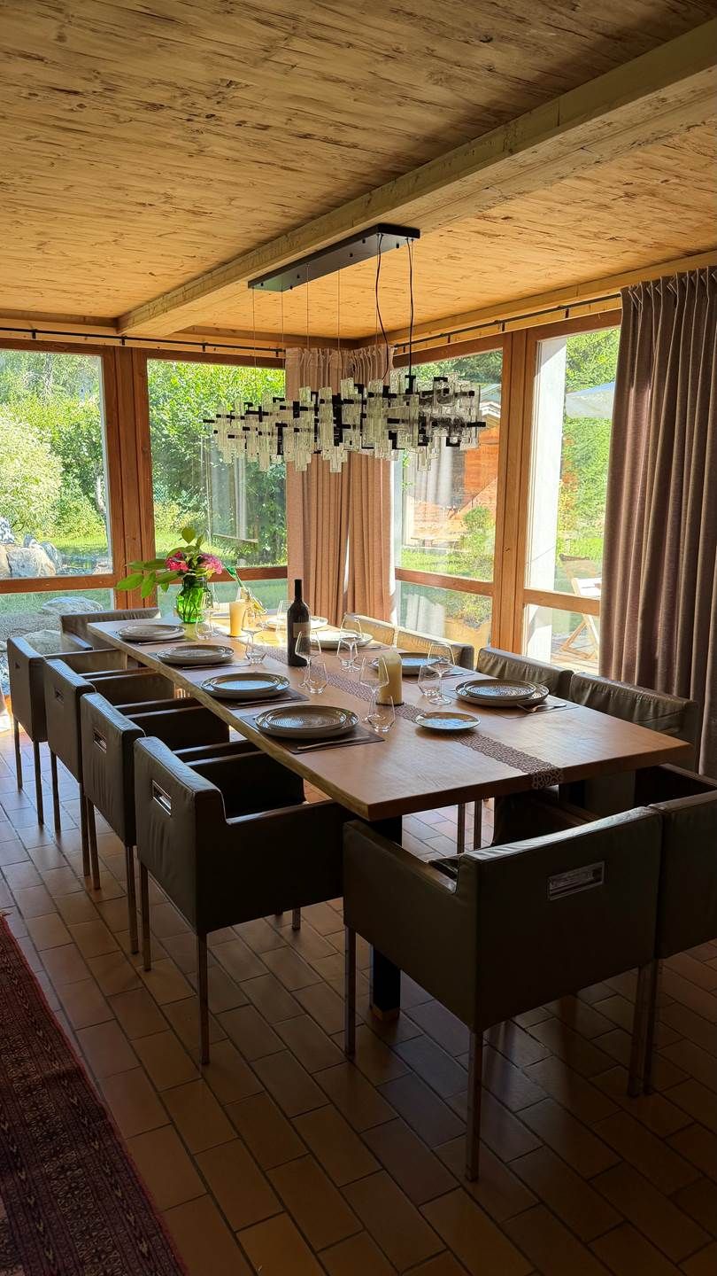 Un espace repas comprenant une longue table, des chaises et un luminaire suspendu.