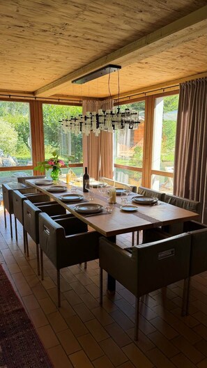 A dining area with a long table, chairs, and a hanging light fixture. - Charming chalet (Saint-Gervais-les-Bains)