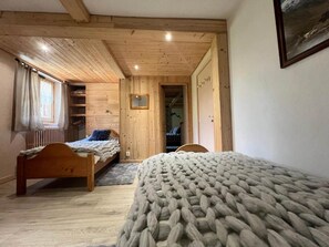 Et soveværelse med to senge i træ, en indbygget garderobe og et lille vindue.