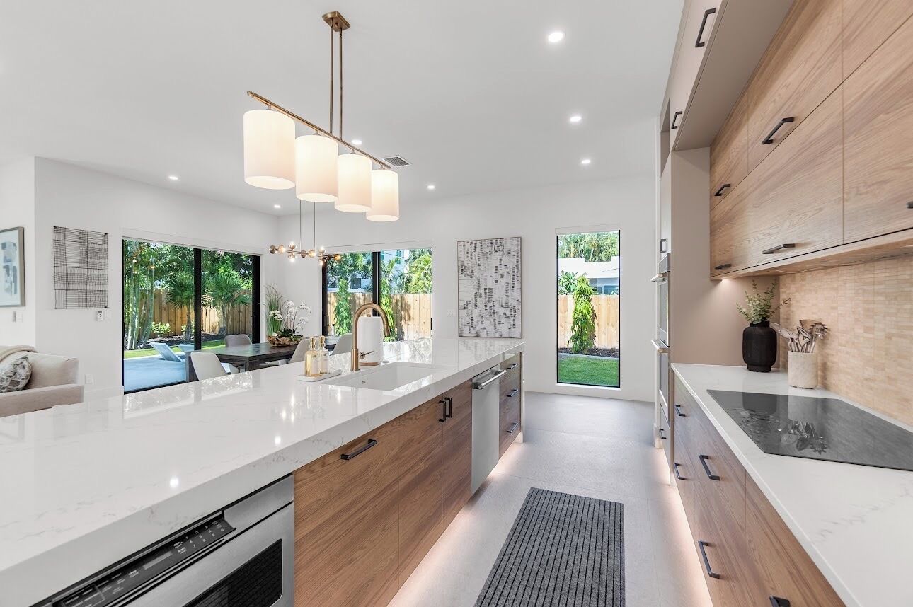 A modern kitchen with a large island, pendant lighting, and a view of the outdoors.