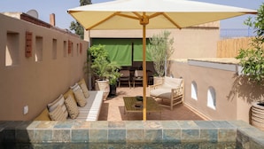 A sunlit patio with a pool, outdoor furniture, and potted plants. - Charming riad with a private rooftop and pool | In the heart of the Medina (Marrakesh)