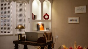 A modern dining area with a marble table, a laptop, and a lamp. There is a bookshelf with books and decorative items. - Charming riad with a private rooftop and pool | In the heart of the Medina (Marrakesh)