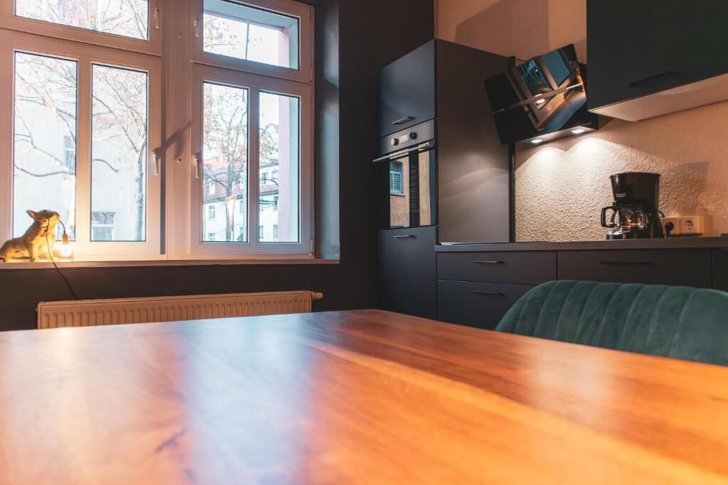 Una cocina moderna con una mesa de madera, horno empotrado y cafetera.