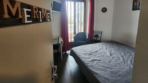 A hotel room with a bed, a desk, a chair, a TV, and a window with curtains. - Charming apartment in the city centre (Luxeuil-les-Bains)