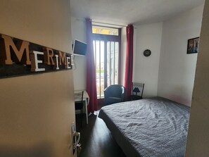 Ein Hotelzimmer mit Bett, Schreibtisch, Stuhl, Fernseher und einem Fenster mit Vorhängen.
