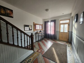 Eine Treppe mit hölzernem Geländer und einem gemusterten Teppich, der zu einer Tür mit Fenster führt.