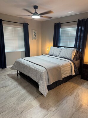 A bedroom with a bed, a ceiling fan, a nightstand, and a window with curtains. - 3-bedroom house in beautiful Sarasota with cool AC breeze and heated pool. (Sarasota)