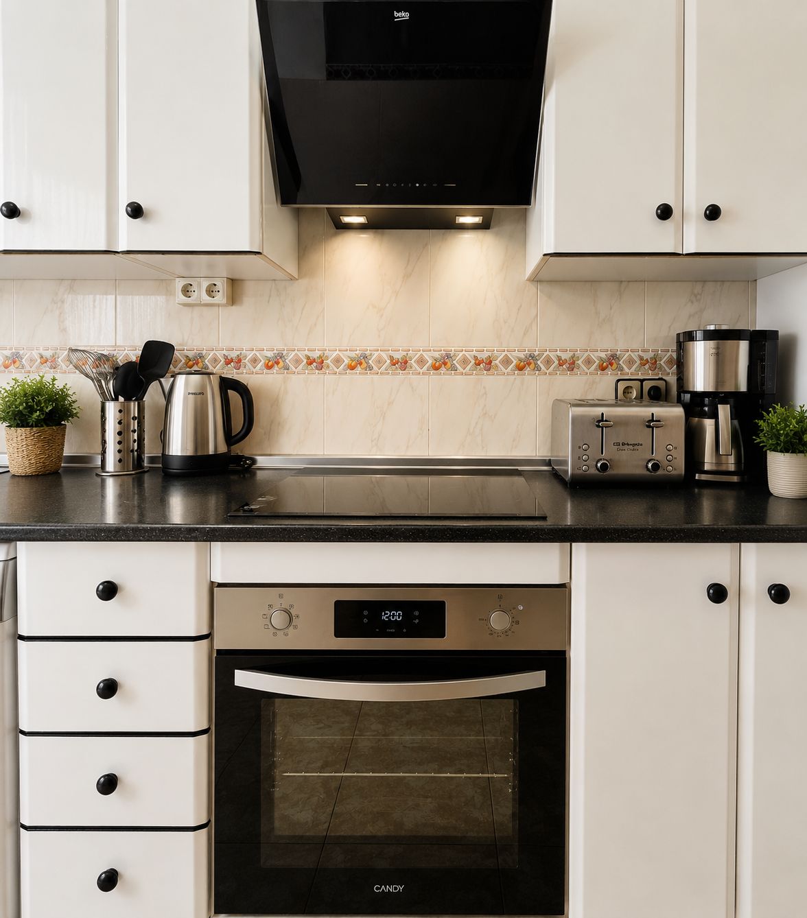 Une cuisine moderne avec des meubles blancs, un four noir, une machine à café et un grille-pain.