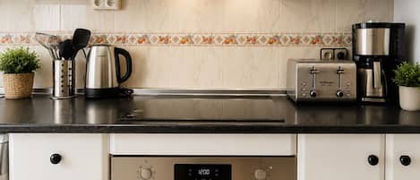 Una cocina moderna con armarios blancos, un horno negro, una cafetera y un tostador.