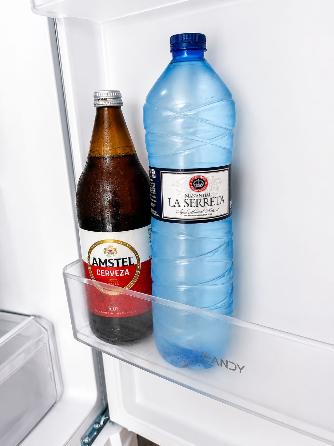 Ein Kühlschrank mit einer Flasche Anstel Cerveza und einer Flasche La Serreta Wasser.