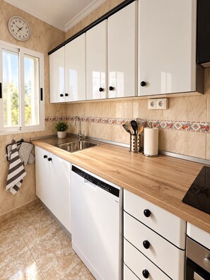 A kitchen with white cabinets, a wooden countertop, a dishwasher, and a sink. - Villa Jenny Private Coastal Retreat Near the Sea (Los Alcázares)