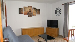 A living room with a sofa, TV stand, and artwork on the wall. - Family apartment, sea view, pets welcome - 6 guests (Gandia)