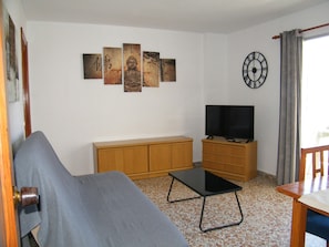 Ein Wohnzimmer mit Sofa, TV-Möbel und Kunstwerk an der Wand.