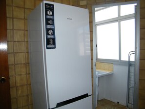 Ein weißer Kühlschrank mit Bedienfeld, das Symbole für Energie und intelligente digitale Steuerung zeigt, einer umsetzbaren Tür und einem Fenster darüber.
