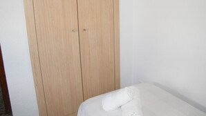 A room with a wooden wardrobe and a bed with a rolled white towel. - Family apartment, sea view, pets welcome - 6 guests (Gandia)