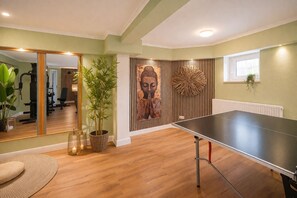 A room with a ping pong table, a large mirror, a Buddha statue, and a gym area. - Villa Manatee - Wellness Apartment with a Balcony (Sellin)