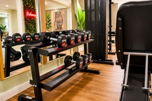 A gym with a weight rack holding dumbbells, a large mirror, and a wall with a Buddha statue. - Villa Manatee - Wellness Apartment with a Balcony (Sellin)