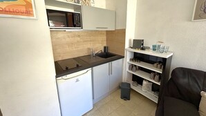 Uma cozinha compacta equipada com micro-ondas, pia e armários.