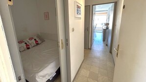 Quarto de hotel com cama, porta, corredor e vista para o exterior.
